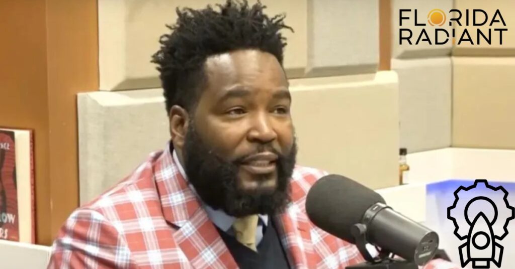 A bearded individual dressed in a red plaid shirt is on air at a radio station.