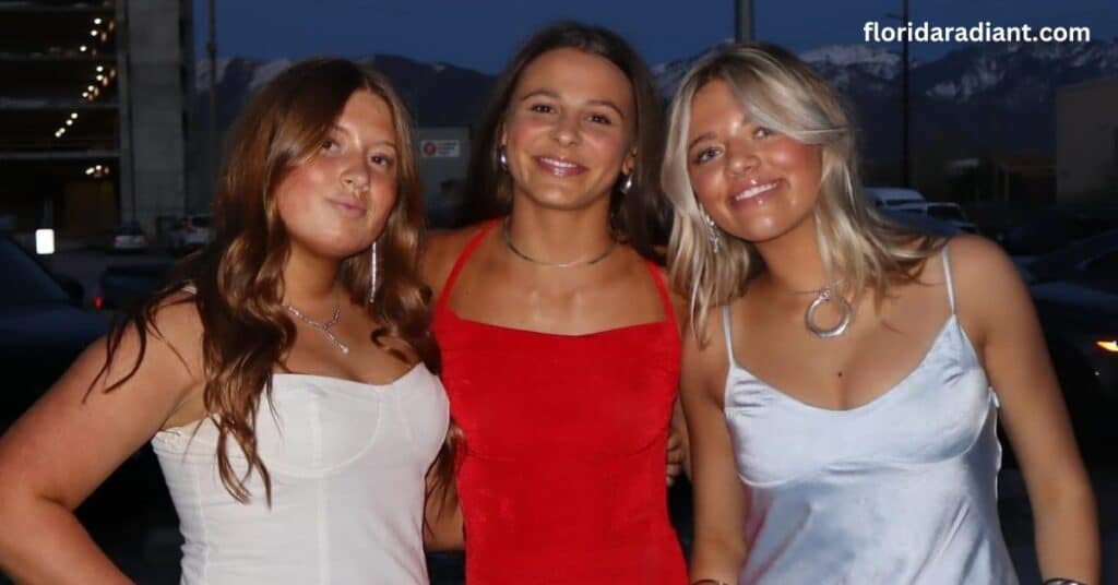 A group of three young women dressed in red dresses stands together, smiling for a picture, radiating joy and friendship.