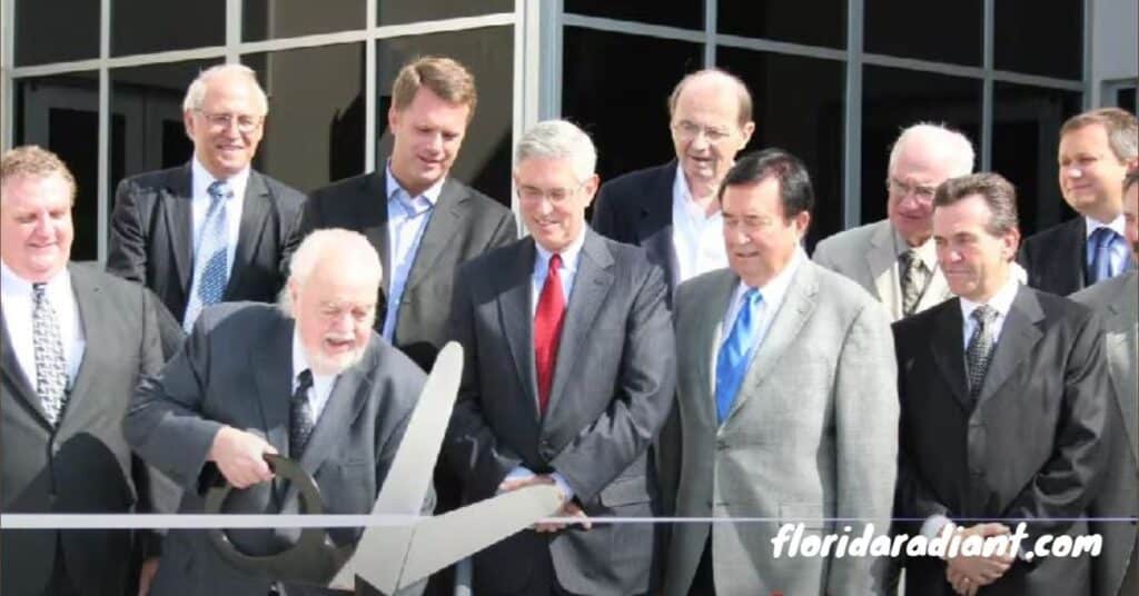 Men in formal attire are cutting a large ribbon with scissors, symbolizing the opening of a new establishment.