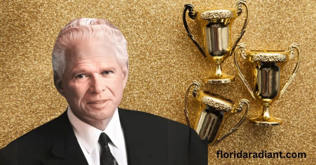 Dressed in a suit and tie, a man is surrounded by an array of gold trophies, symbolizing his accomplishments.